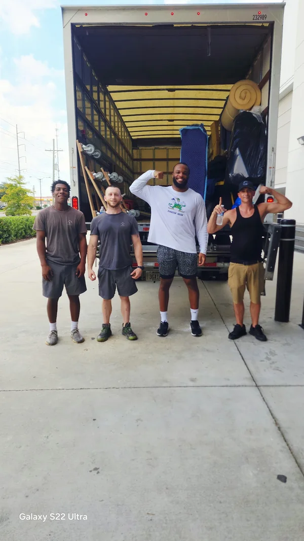 Four Next Nest team members standing together in front of a loaded moving truck
