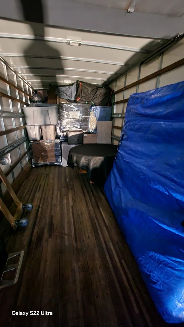 Boxes, storage containers and blanket-wrapped furniture arranged in a moving truck